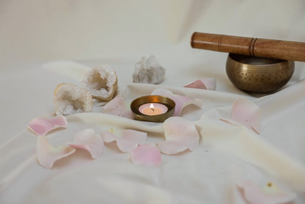 A peaceful alter with candles, crystals and a singing bowl.